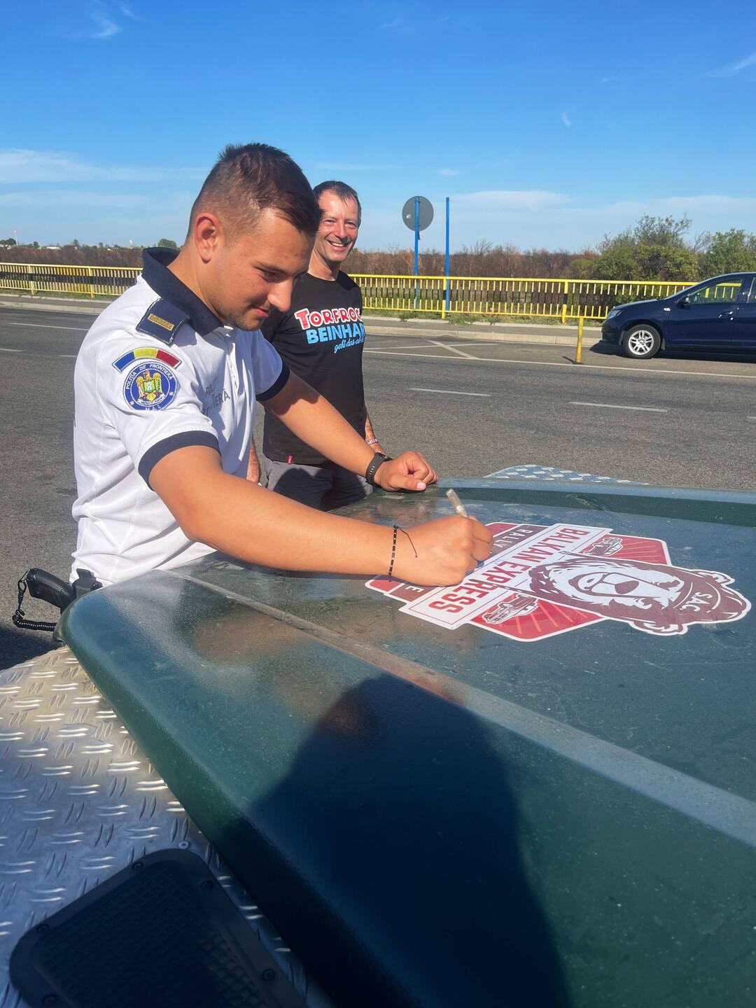 Ein rumänischer Grenzbeamter spendiert eine Unterschrift auf unterem Rallyeaufkleber
