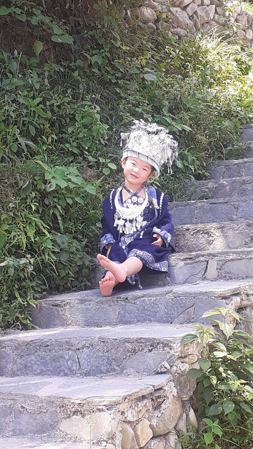 Ein Miao Mädchen spielt auf der Treppe