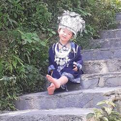 Ein Miao Mädchen spielt auf der Treppe