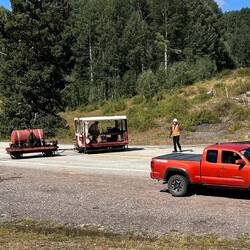 The train has passed. Now, the railroad safety man controls the crossing as the fire patrol passes.