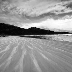 Sand streams blowing along the beach