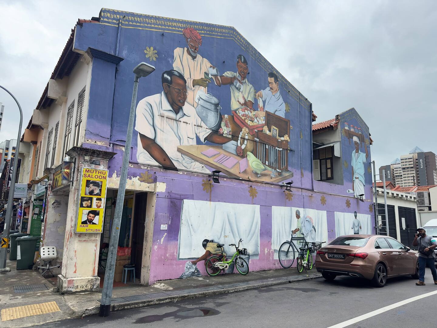 This mural depicts, among other things, a man making shaved ice, another making a garland.