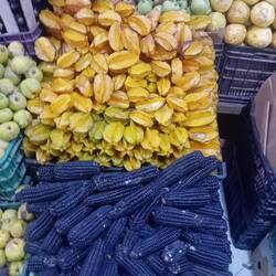 At the market. Typical produce of Peru: Carambolas (star fruit) and black corn