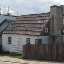 An early log building. The windowed corner shows the log construction under the siding.