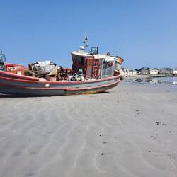 das einzige Fischerboot in der Bucht, im Hintergrund die verfallenen Häuser der Fischerei bis 1997