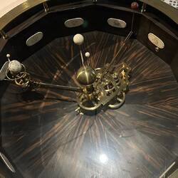 This machine is an Orrery. It rotates and everything in it rotates. The brass knob is the sun.