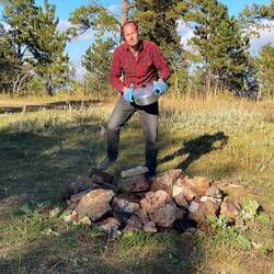 Aron gießt Nudelwasser über der Feuerstelle ab.