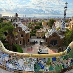 Bench with two Gaudi designed administrative buildings. Sagrada Familia in the distance