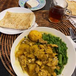 Chicken curry with roti, potatoes, fried egg, beans, cabbage