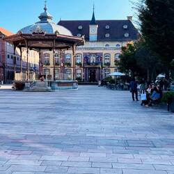 Plaza de armas rodeada de fachadas elegantes y cafés animados.