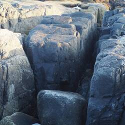 The dyke of dark rock split toward the shore
