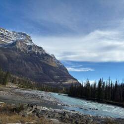 Zwischen schneebedeckten Gipfeln und dunklen Wäldern zieht der Fluss seine Bahn durch die Wildnis.