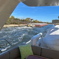 A tug pushes past with 4 barges of heavy aggregate. A blooper follows, keeping his distance.