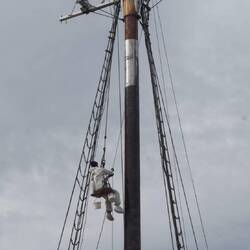Man being hoisted up the mast