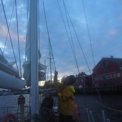 Crewman lowers the Mizzen Sail as the captain pilots the boat