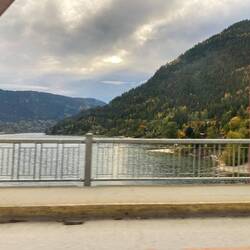 Zwischen Brückenpfeilern fällt der Blick auf den stillen Kootenay Lake und die herbstlichen Hänge.
