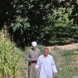 The aparent land owner inspects his land while the administrator walks behind taking notes.