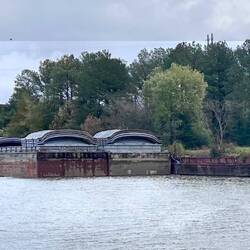 River scene - transient barges are tied to a dock that is actually an old barge beached on the bank