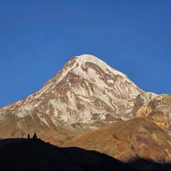 Morning view of Kazbek, with the silhouette of Gergeti Trinity Church in the foreground