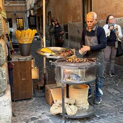 Rumgedreht, weg vom Trevi; steht er da, der Maronenverkäufer, malocht für ein besseres Leben