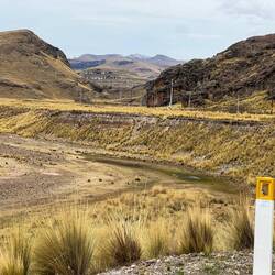 In front the river bed, far behind there is a dusting of snow on the mountain tops