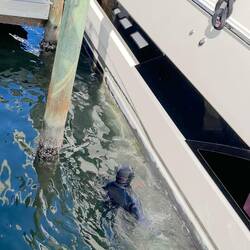 Diver scraping the hull of a motor yacht