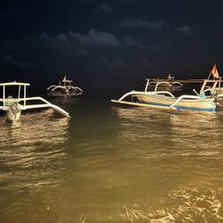 Fishing boats bob gently on the shore at night