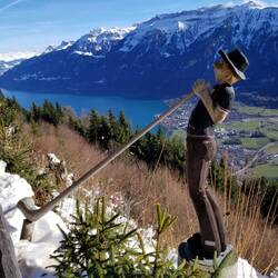 Playing the alpinhorn against the backdrop of Laucherhorn in front of Lake Brienze