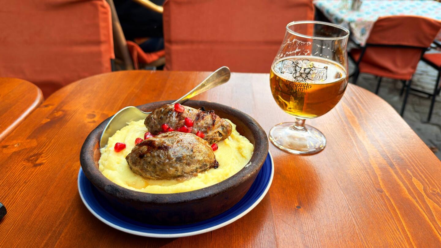 Meat sausage, puréed potatoes, pomegranate, and local beer