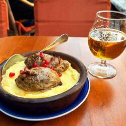 Meat sausage, puréed potatoes, pomegranate, and local beer