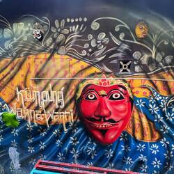 There are murals on walls featuring animals, masks, laughing cartoons.