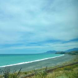 Een donker strand met super blauwe zee