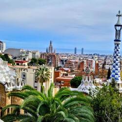 View from path, showing Gaudi buildings with Sagrada Familia and Mediterranean in the background