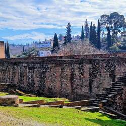 Alhambra walls near ruins of public baths. See snowy mountains in the distance
