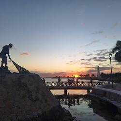 Fisherman statue and the ferry pier at sunset.