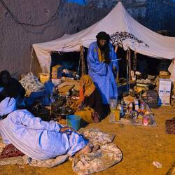 Nomad families at night. Mats on the ground, children in the lap, food cooking on the gas stove