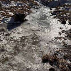 Das Wasser fließt unter der Eisschicht