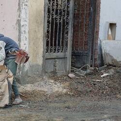 Mit der Hand misst das Bürschchen den Zement ein, vermischt es mit Sand. Er ist so um die 10 Jahre