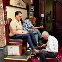 Schuhputzer mit weißem Hemd und roter Fliege in den Arkaden