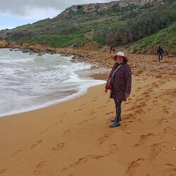 Ramla Bay, Mixta Cave at the top left of the cliff behind