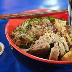 Suppenkaspar Roman futtert sehr scharfe Bakso Suppe mit Fleischbällchen am Nachtmarkt.