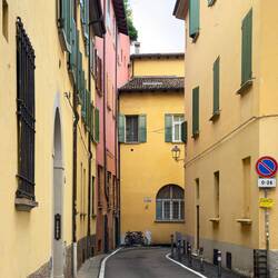 A touch of pink on a yellow street — Bologna, Italy.