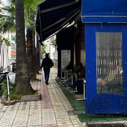 Cafe seats face out and men sit there watching women.