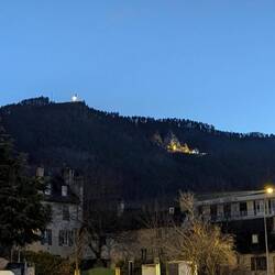 Ein großes beleuchtetes Kreuz auf dem Gipfel und eine Kirche unterhalb