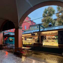 Vendor stalls outside the columns of the portico @ Piazza Aldrovandi — Bologna, Italy.
