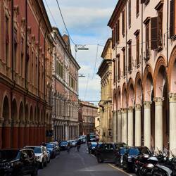 A street lined with porticos and vehicles ... common sight in the city — Bologna, Italy.