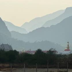 Mountains layered hazily one in front of the other, with golden Buddhas sitting calmly at their base