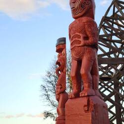 Im Park stehen Maori Figuren um einen Brunnen