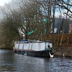 Boat moored next to an industrial site with a lot of fly tipped rubbish