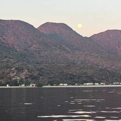 Moon setting behind mountains